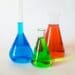 Three erlenmeyer flasks with blue, green and red chemical solutions